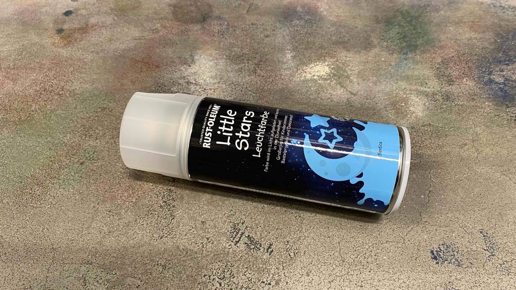 Leuchtfarbe getestet: Auf einem Betonboden liegt horizontal eine Dose.