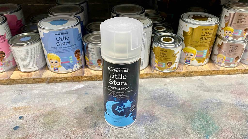 Im Test: Vor einem Regal steht eine Dose Leuchtfarbe.