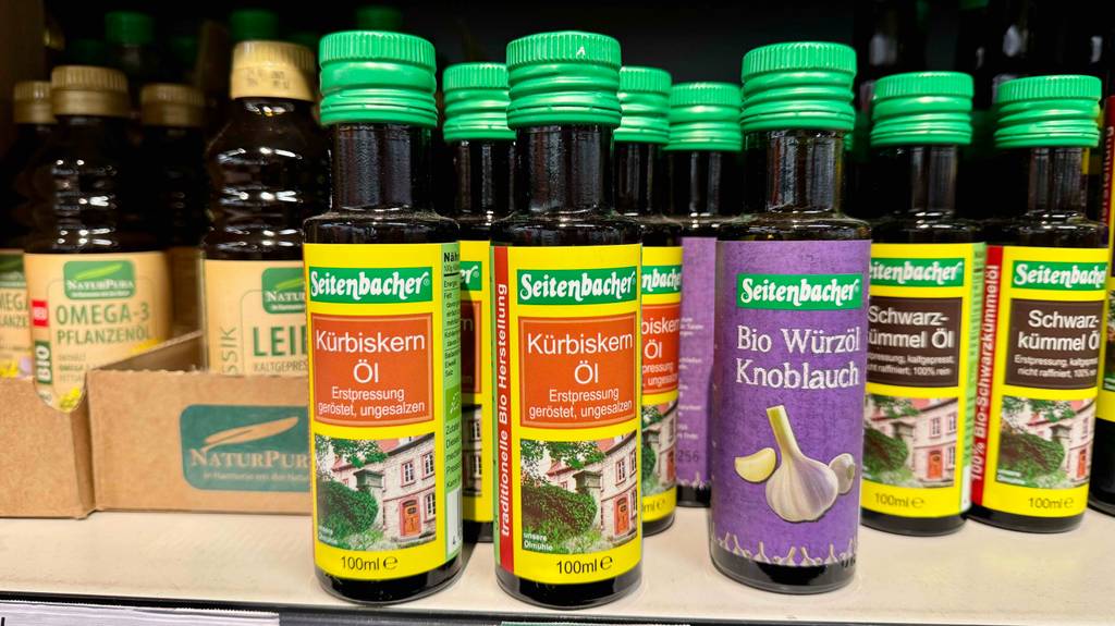 Getestet: mehrere Flaschen Bio-Kürbiskernöle stehen in einem Regal neben andere Öle.
