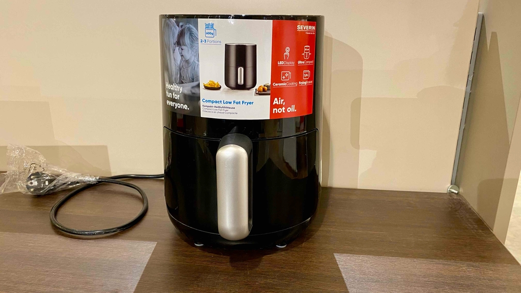 Kleine Heißluftfritteuse-Test: Ein Gerät von vorne vor einer hellen Wand.