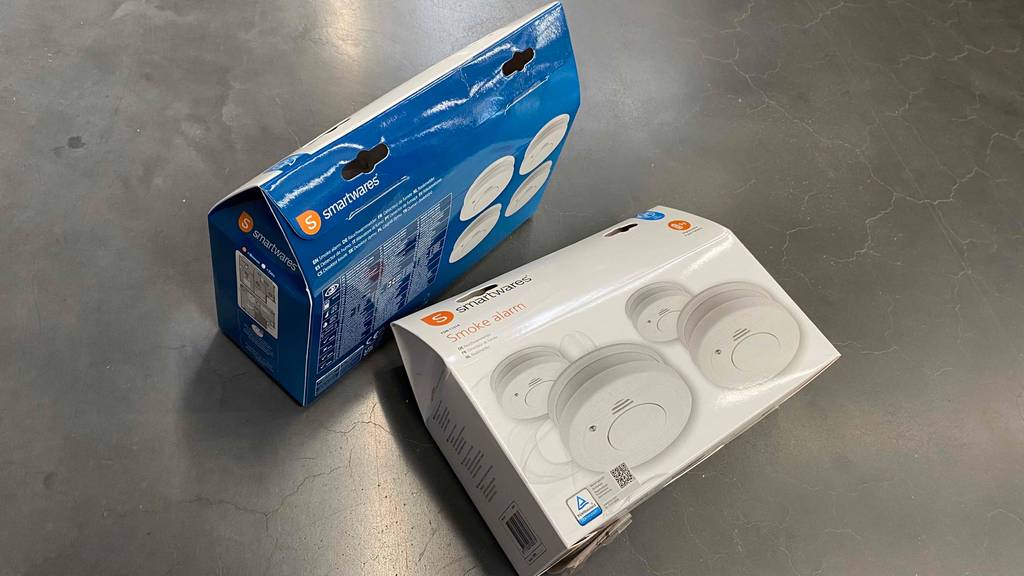Im Test: Zwei Funkrauchmelder-Sets nebeneinander auf einem grauen Untergrund, eine stehend, eine liegend