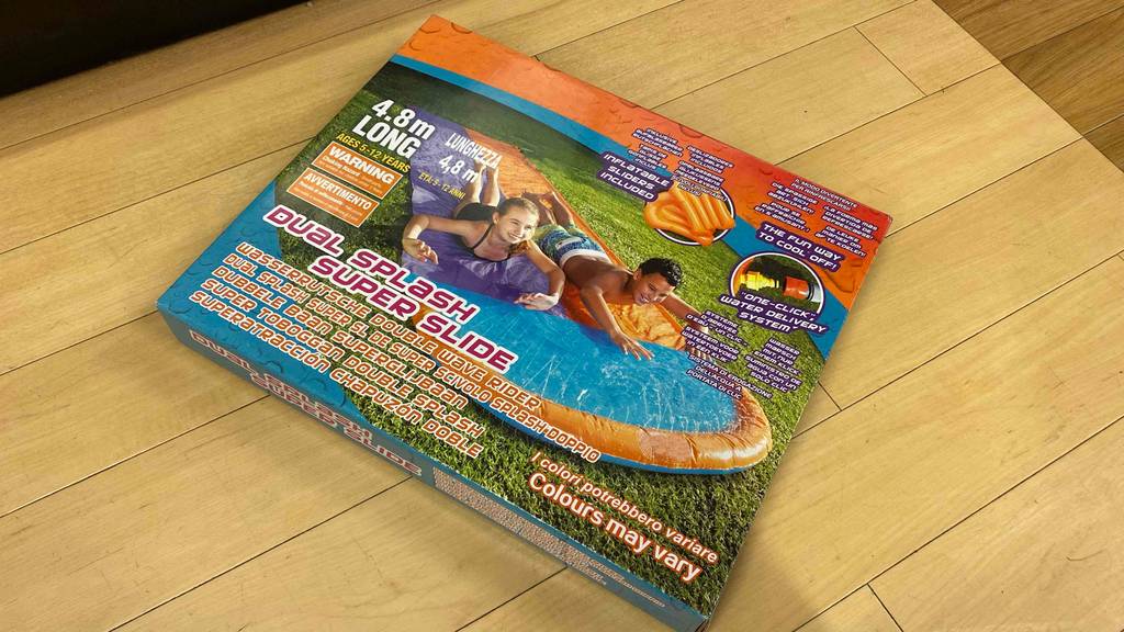 Wasserrutsche getestet: Eine verpackte Wasserrutsche liegt quer auf einem Holzboden.