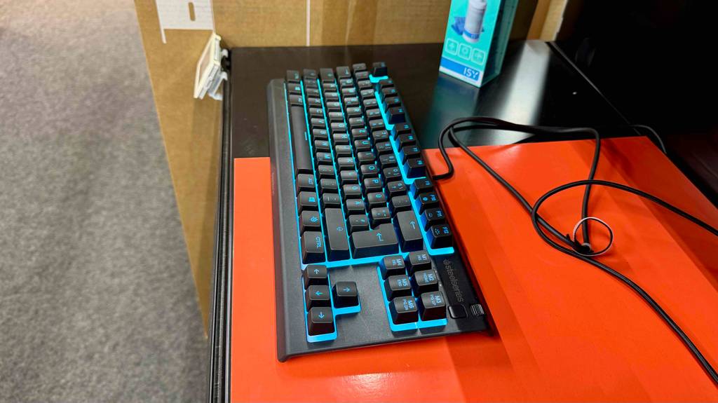 Die getestete SteelSeries-Tastatur befindet sich mit beleuchteter Tastatur auf einem orangefarbenen Tisch.