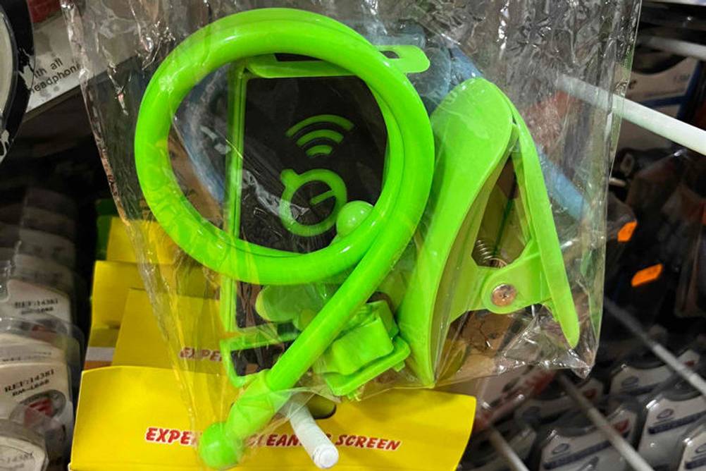 Tablet-Halterung-Test: grüne Tablet-Halterung in durchsichtiger Verpackung in eeinem Regal hängend.