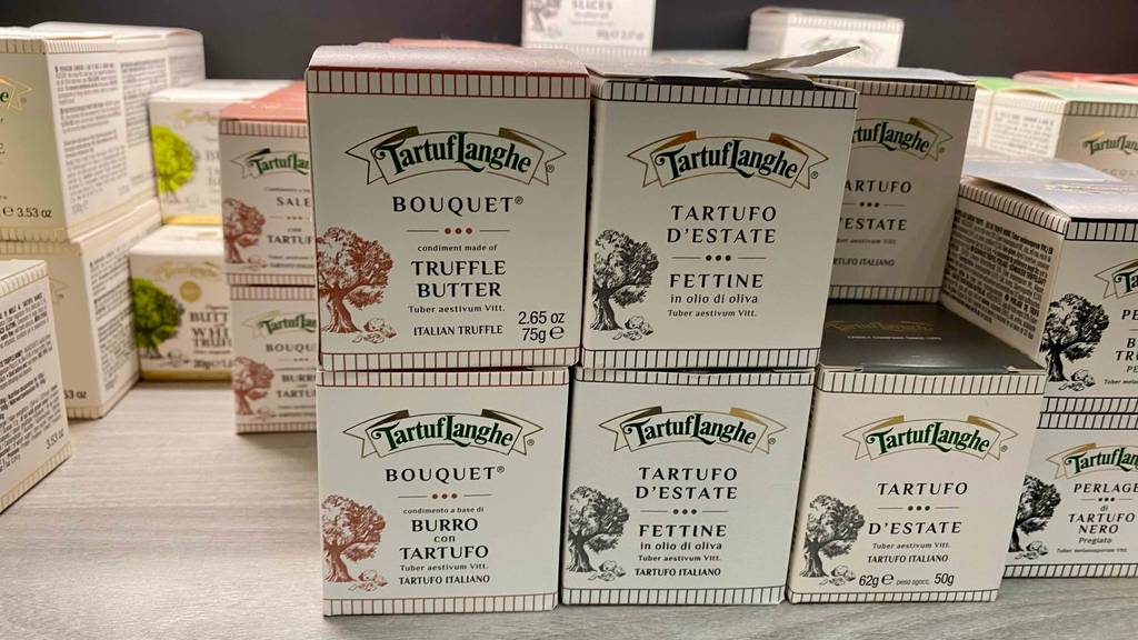Im Test: Mehrere Packungen Trüffelbutter gestapelt neben anderen Produkten auf einer Holzfläche.