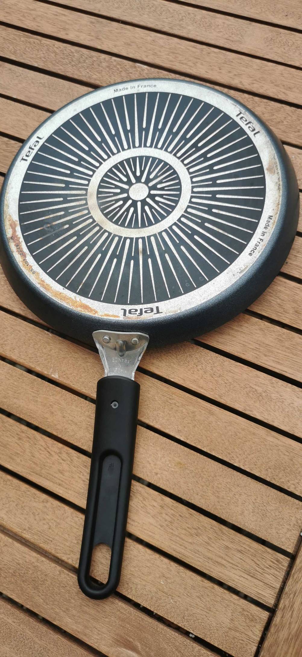 Auf einem Holztisch liegt eine getestete Crêpes-Pfanne mit der Rückseite nach oben.