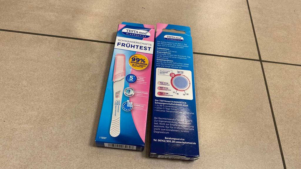 Frühschwangerschaftstest im Test: zwei Packungen Frühschwangerschaftstests auf einem Boden liegend - einer auf der Rück- und einer auf der Vorderseite.