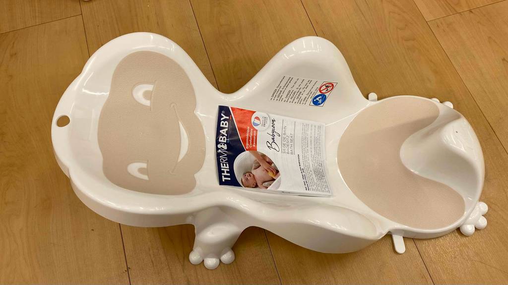 Im Test: Auf einem Holzboden steht ein Badewannensitz für Babys.