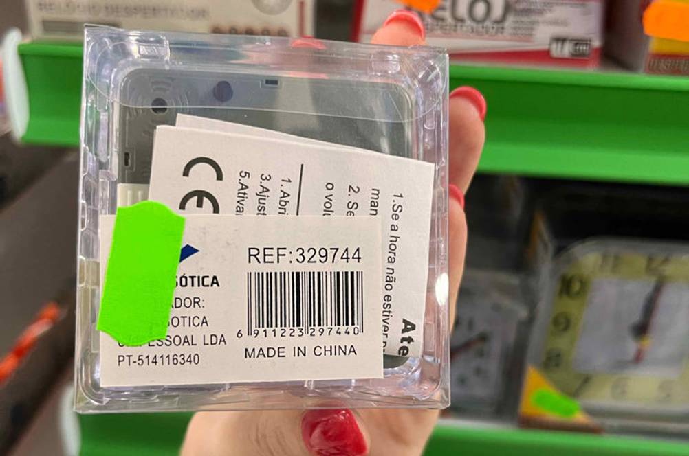 Reisewecker-Test: Verpackter Reisewecker mit Barcode und Herkunftsland wird in der Hand gehalten.