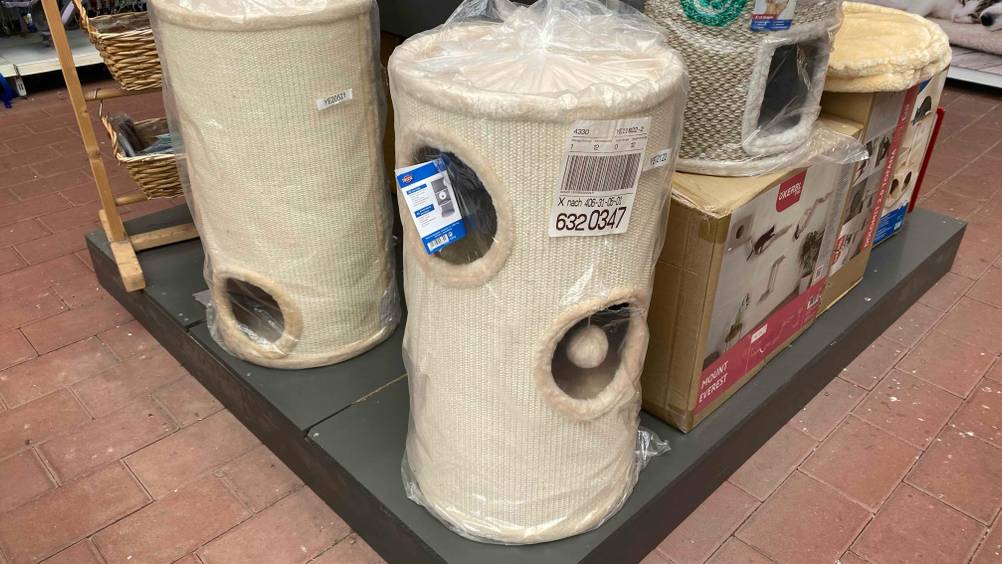 Im Test: Eine Kratztonne steht auf einem grauen Sockel neben anderen Produkten.