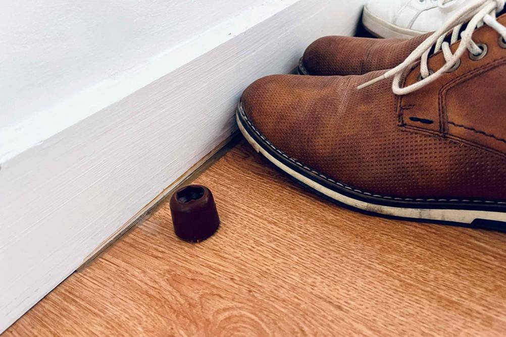 Türstopper getestet: Stopper neben einem Paar Schuhe auf Holzboden