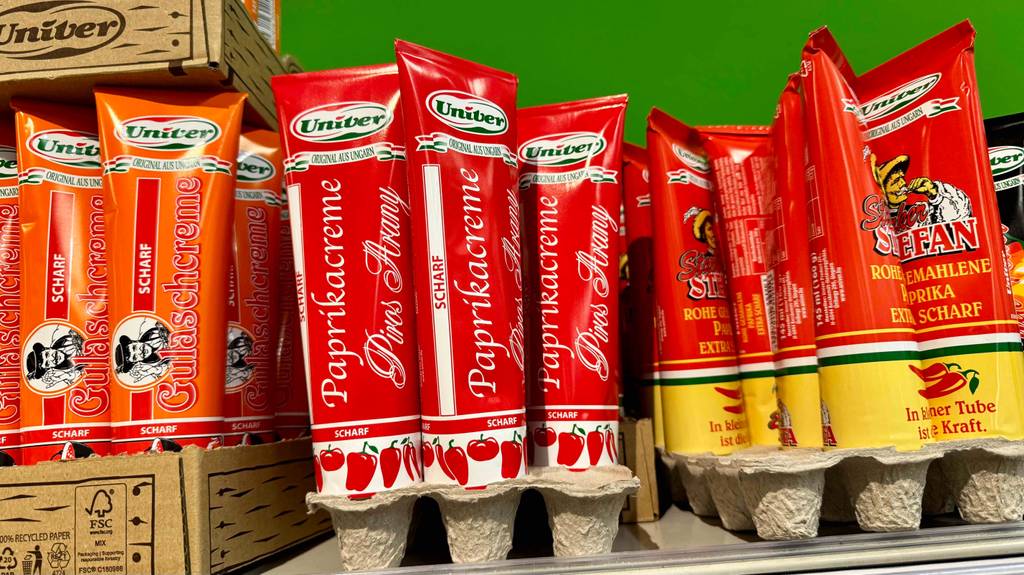 Mehrere getestete Paprikapasten sind in einem Regal einsortiert, neben anderen Produkten.