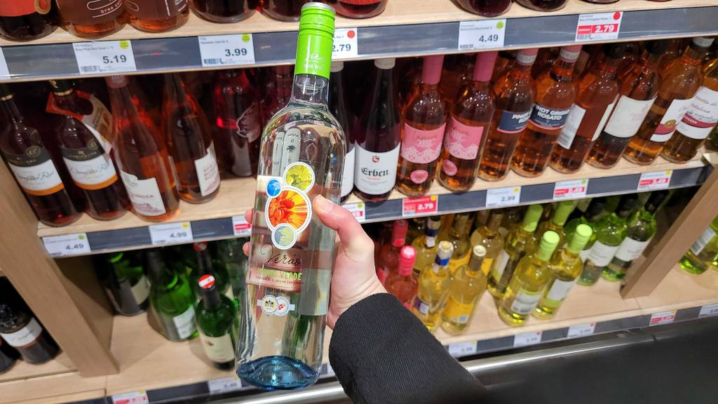 Eine Flasche getesteter Vinho Verde wird in der Hand vor einem Regal gehalten.