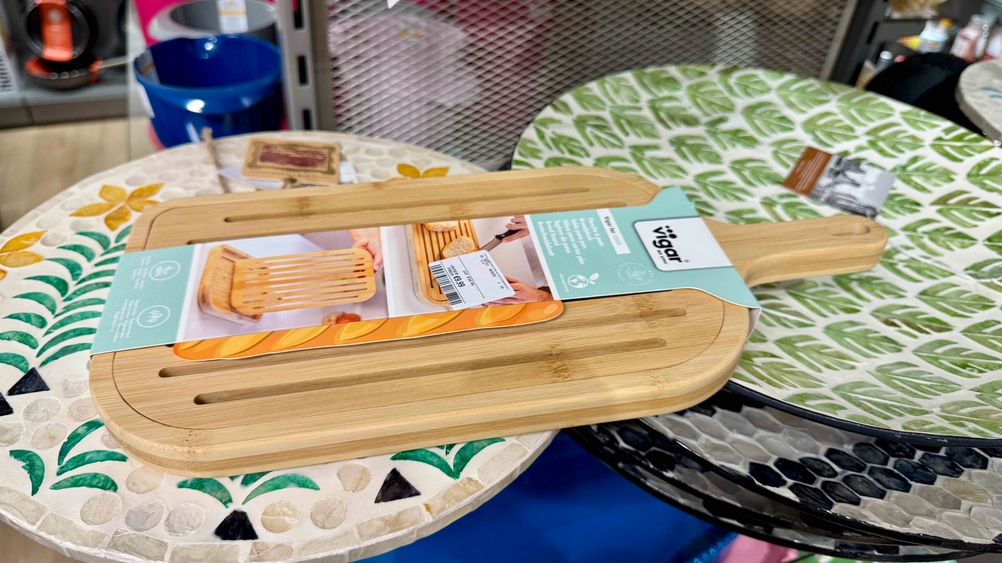 Ein getestetes Brotschneidebrett liegt auf bunten Tellern.