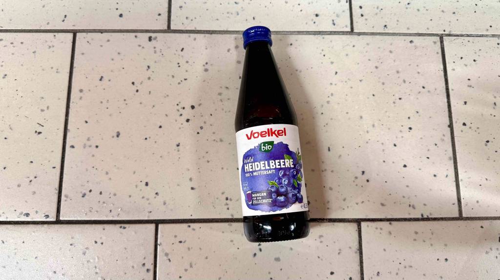 Ein getesteter Saft liegt auf einem Fliesenboden, wobei hier die Vorderseite ersichtlich ist.
