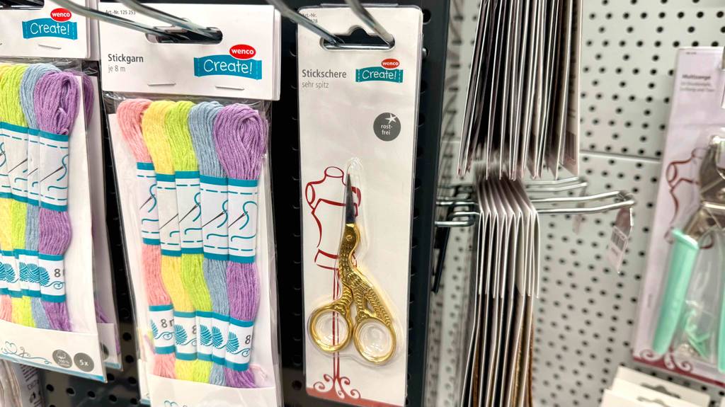 Test: Eine Stickschere hängt in einem Regal neben anderen Artikeln.