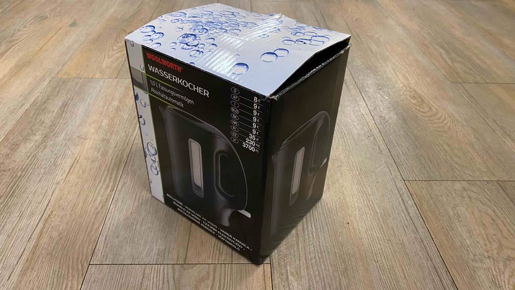 Im Test: Ein verpackter Wasserkocher 1 Liter steht auf einer Holzfläche.