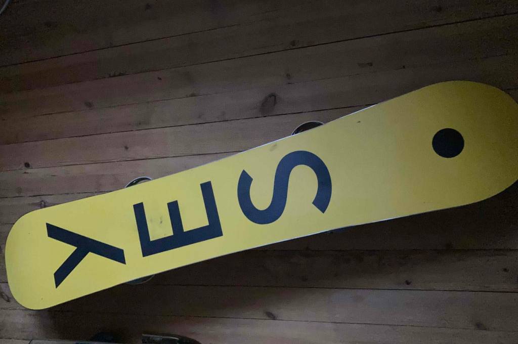 Snowboard getestet: Ein Board liegt mit der Rückseite nach oben auf einem Holzboden.