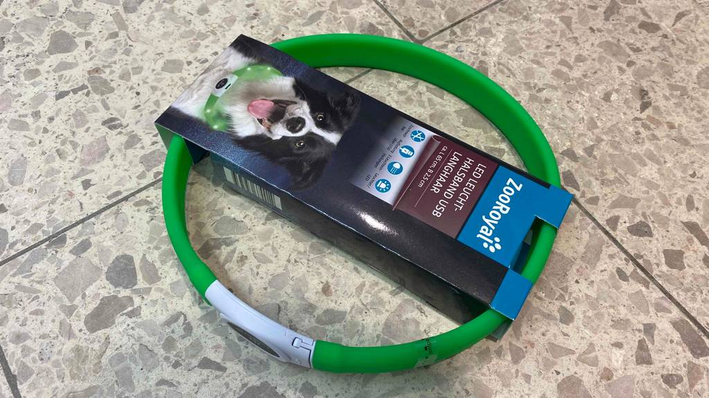 Im Test: Ein verpacktes Leuchthalsband für den Hund liegt auf einem Steinboden.