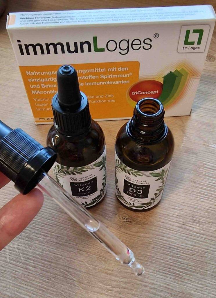 Vitamin-D3-Test: Die Pipette von Vitamin-D3-Tropfen wird vor den Vitamin-K2- und Vitamin-D3-Fläschchen gehalten.