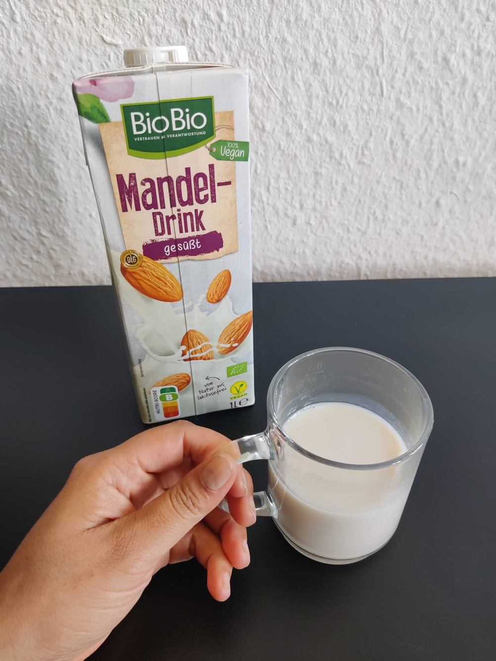 Mandelmilch in einem Glas und Verpackung zu sehen.