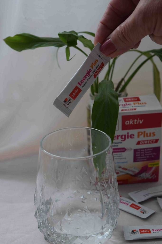 Energieplus Päckchen mit Koffein wird in ein Glas gegeben.