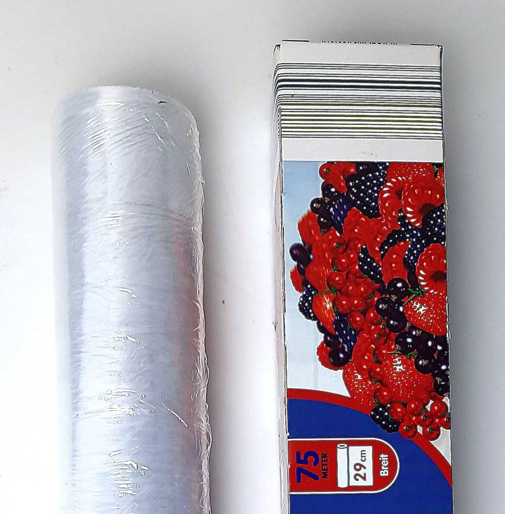 Eine Rolle getestete Küchenfolie liegt neben der Verpackung.