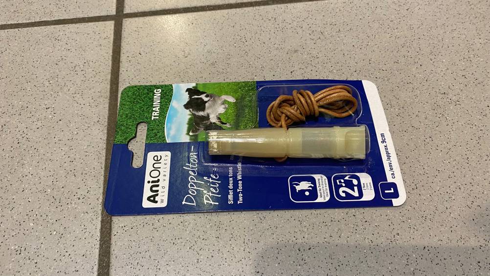 Im Test: Eine Hundepfeife in ihrer Originalverpackung liegt auf einem Fliesenboden.