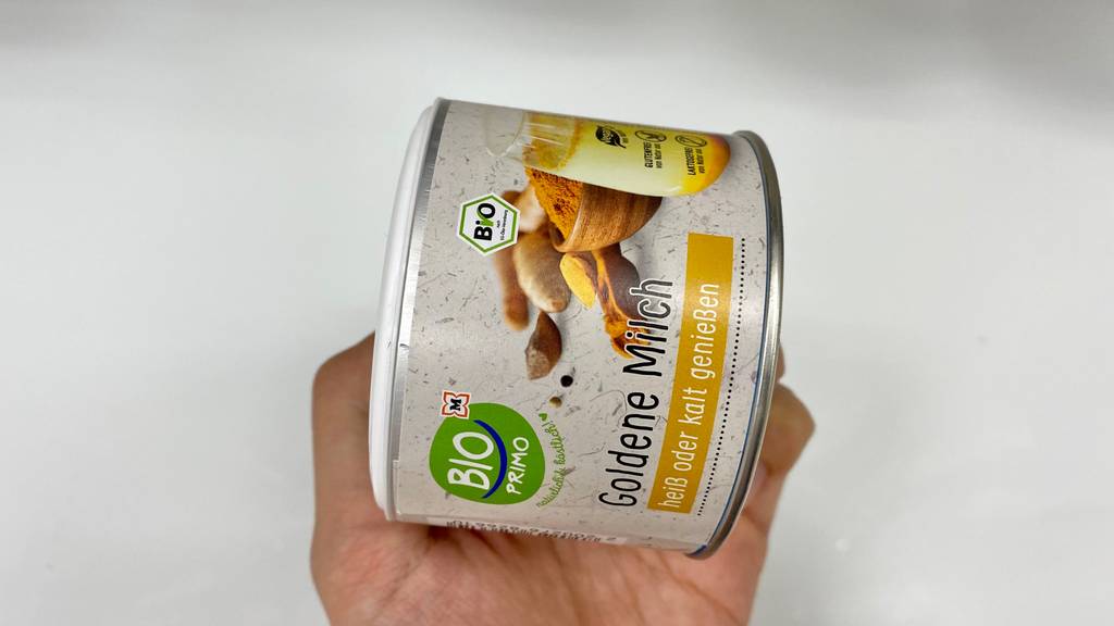 Goldene-Milch Pulver im Test: Eine Hand hält eine Dose vor einen hellen Hintergrund