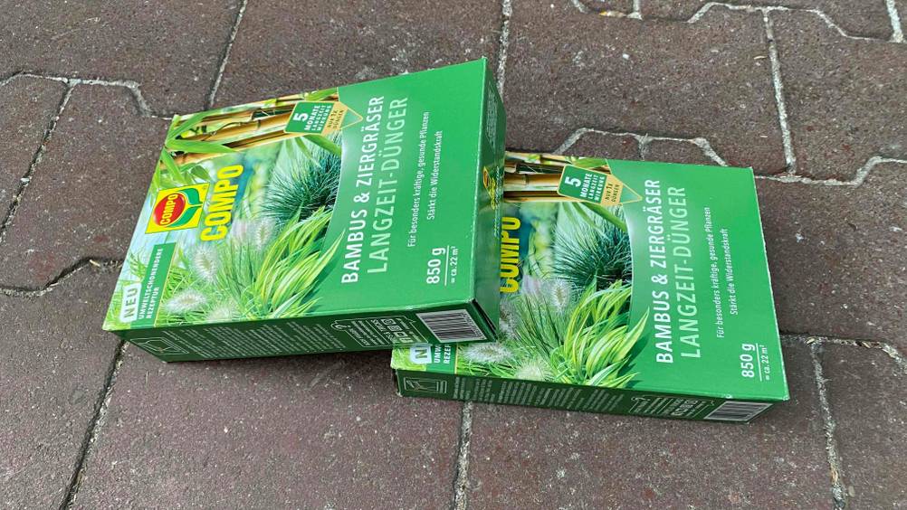 Bambusdünger im Test: Zwei Packungen liegen leicht übereinander auf einem Pflaserstein