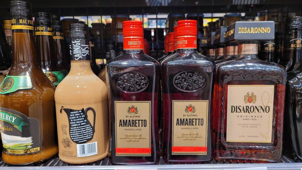 Amaretto im Test: Amaretto-Flaschen stehen in einem Regal neben anderen alkoholischen Getränken.