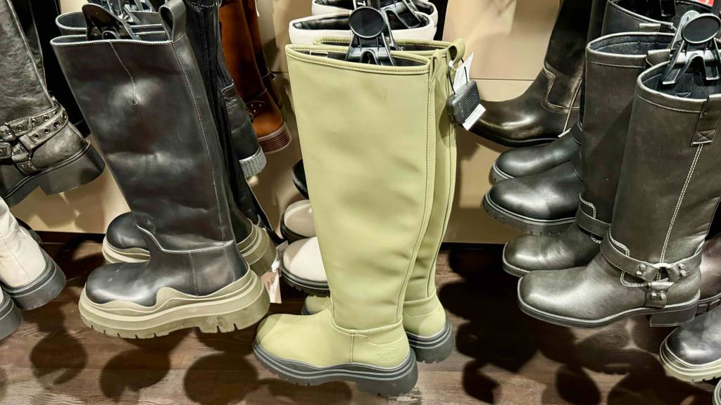 Ein Paar getestete Winter-Gummistiefel hängen in einem Regal neben anderen Gummistiefel.