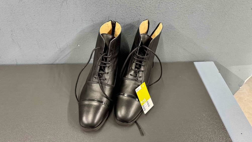 Die getesteten Lederreitstiefel stehen mit geöffneten Schnüsenkeln vor einer Wand.