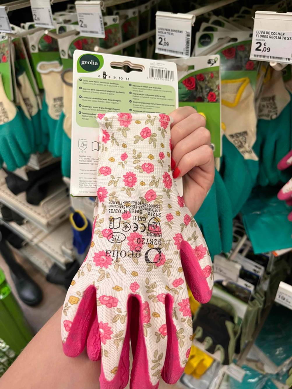 Schnittschutzhandschuhe getestet: Eine Hand hält ein Paar Handschuhe vor ein Regal