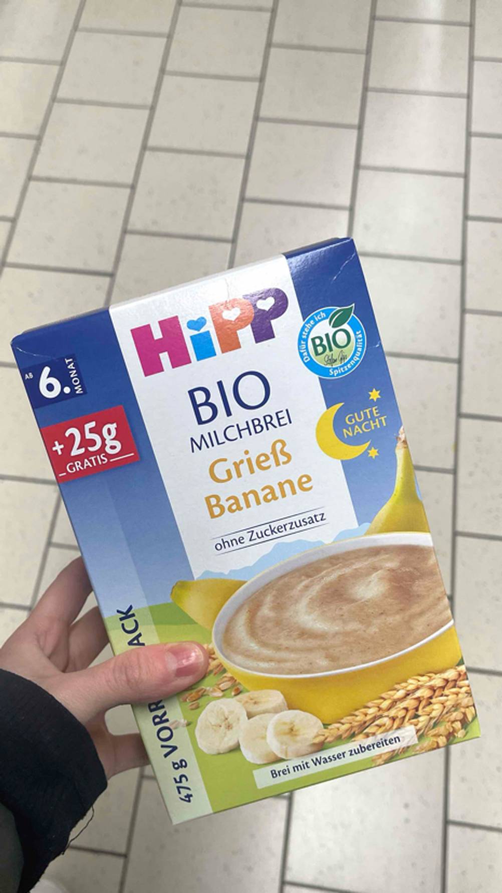 Der getestete Getreide-Obst-Brei ab dem 6. Monat in der Geschmacksrichtung Grieß und Banane wird in der Hand gehalten.