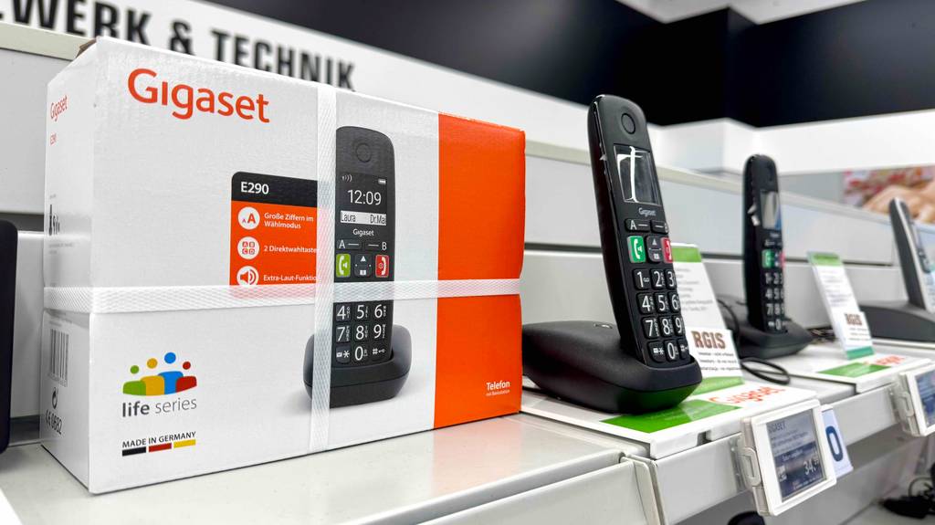 Das Gigaset-Dect-Telefon im Test steht neben weiteren Telefonen inklusive Ladestation auf einem Ausstellungsregal im Verkaufsbereich.