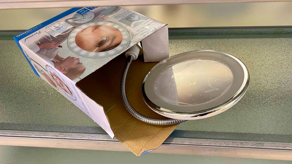 Aus seiner Verpackung schaut ein getesteter beleuchteter Kosmetikspiegel hervor.