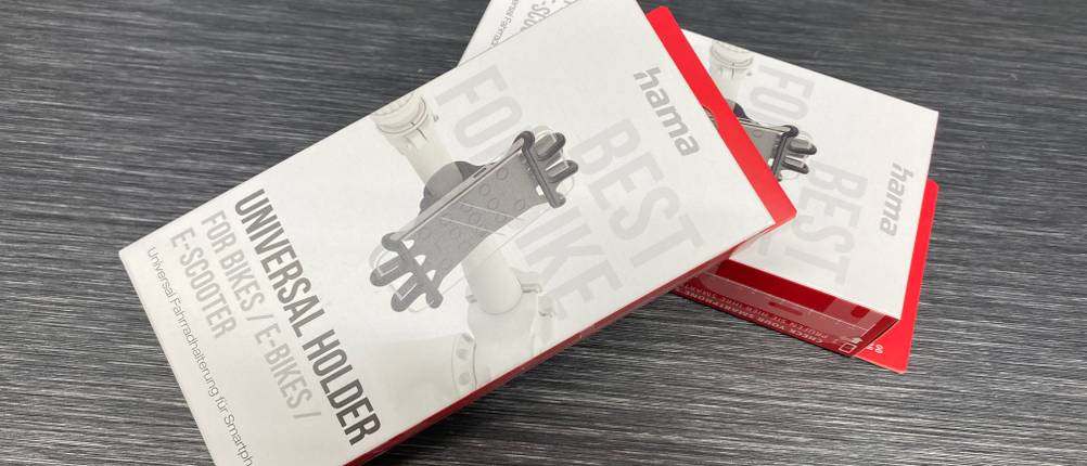 Im Test: Auf einer Holzfläche liegen zwei verpackte Fahrrad-Handyhalterungen leicht übereinander.