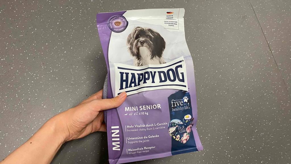 Hundefutter-Senior im Test: Hundefutter wird in der Hand über einem grauen Boden gehalten