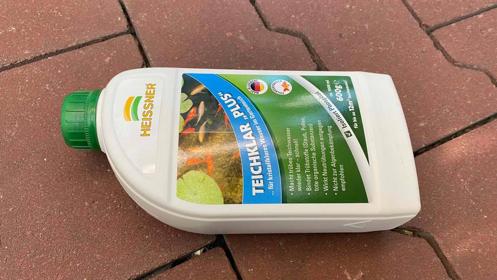 Teichklar im Test: Flasche von Teichreiniger auf einem roten Steinboden.