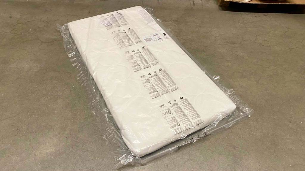 Matratze-60x120 im Test: eine Matratze in Plastikhülle liegend auf einem Boden.