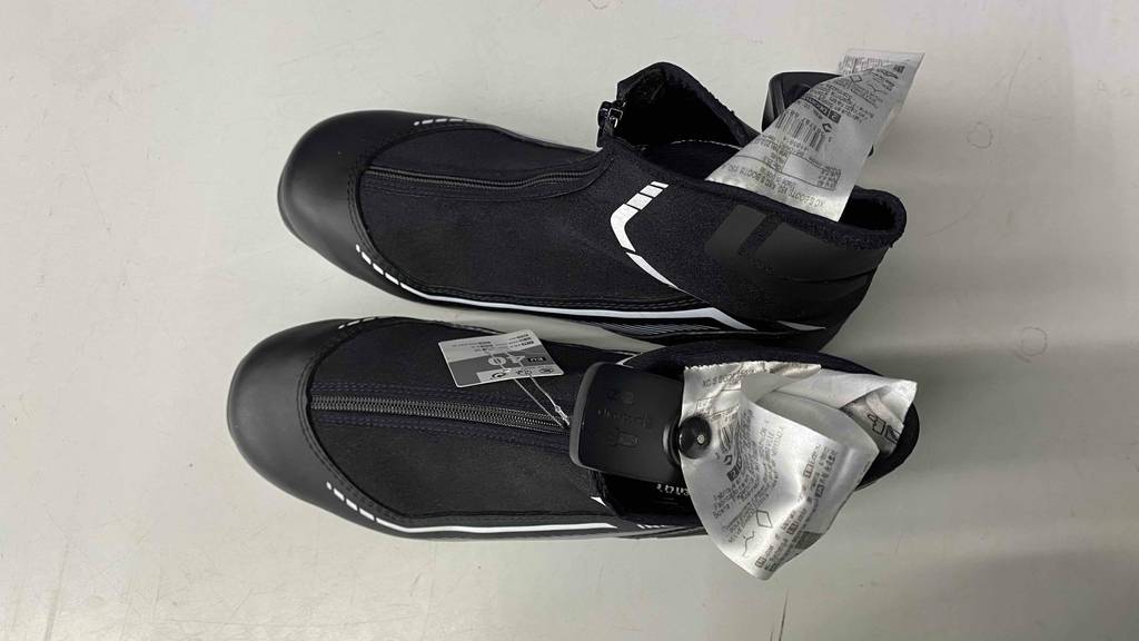 Langlaufschuh im Test: shwarze Langlaufschuhe mit Reißverschluss stehen auf einer weißen Fläche.
