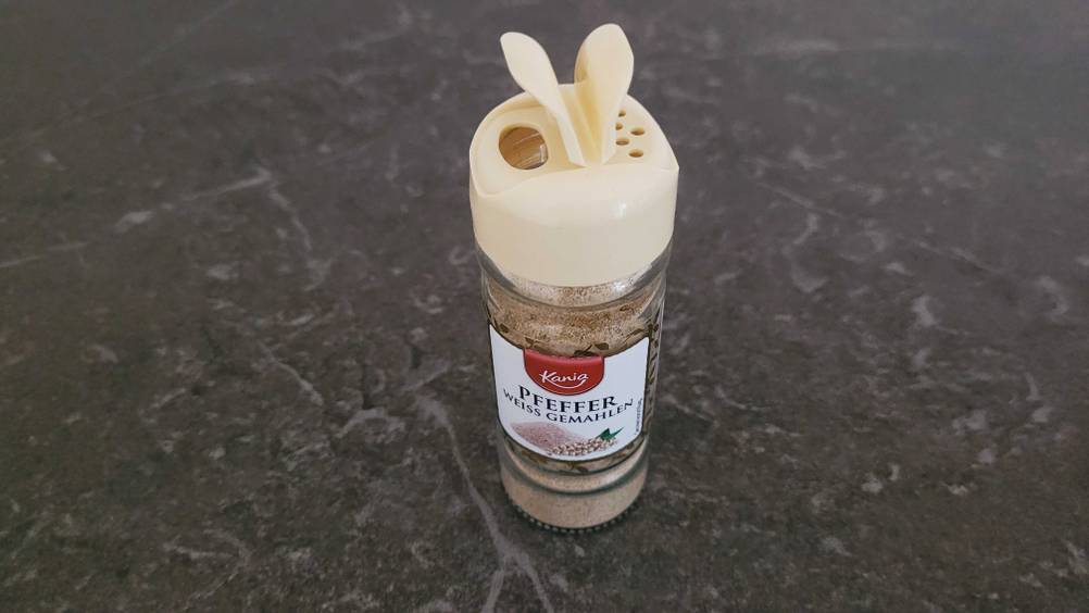 Weißer Pfeffer getestet: Ein Glas Pfeffer mit offenem Deckel steht auf einer dunklen Oberfläche