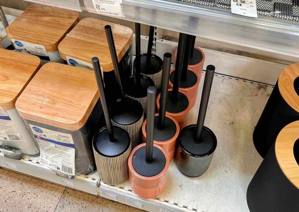 Unterschiedliche getestete Klobürsten inklusive Standbehältnis auf einem Einkaufsregal.
