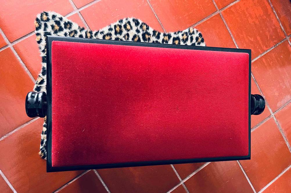 Im Test: Eine Klavierbank von oben auf einem Teppich stehend.