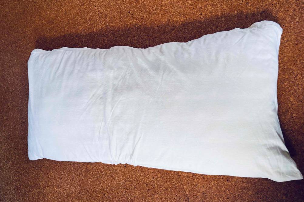 Ein getestetes Kopfkissen 40 x 80 von oben auf einer Holzfläche.