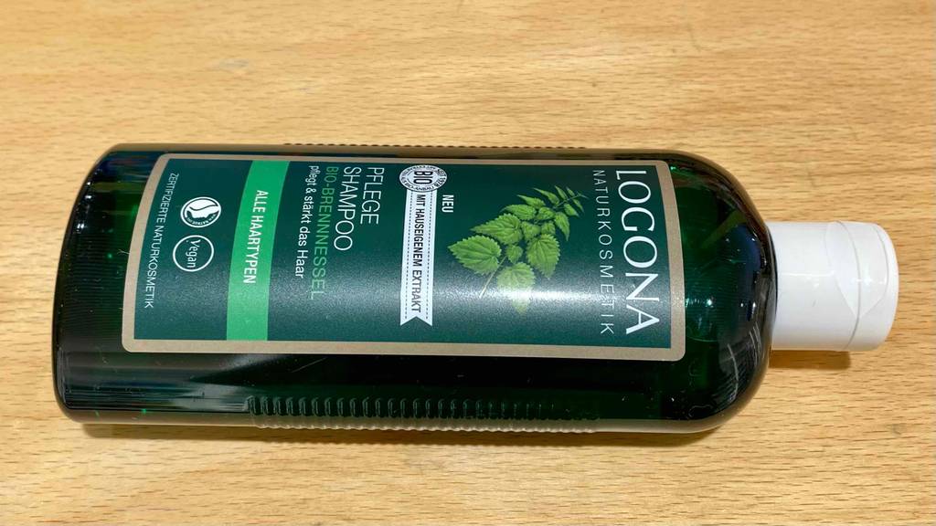 Brennessel-Shampoo im Test: Eine Flasche liegt auf Holzfläche