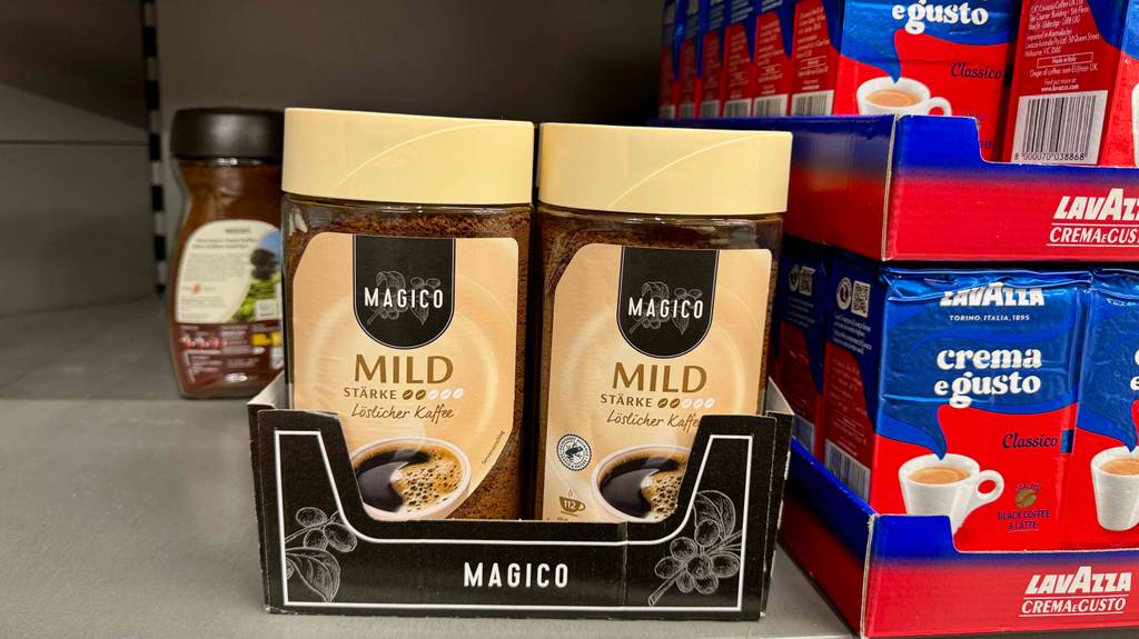 Mehrere Glasbehälter, mit dem getesteten milden Kaffee darin, stehen in einem Karton, der sich in einem Regal befindet.