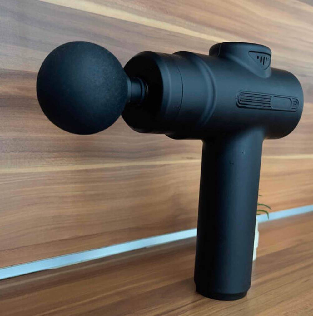 Mini-Massagepistolen-Tests: Ansicht des schwarzen Modells vor einem Holzhintergrund.