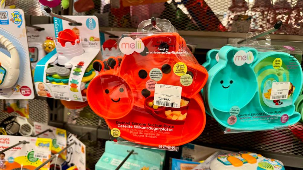 Ein getestetes Kindergeschirr aus Silikon in Form eines Marienkäfers hängt in einem Regal.